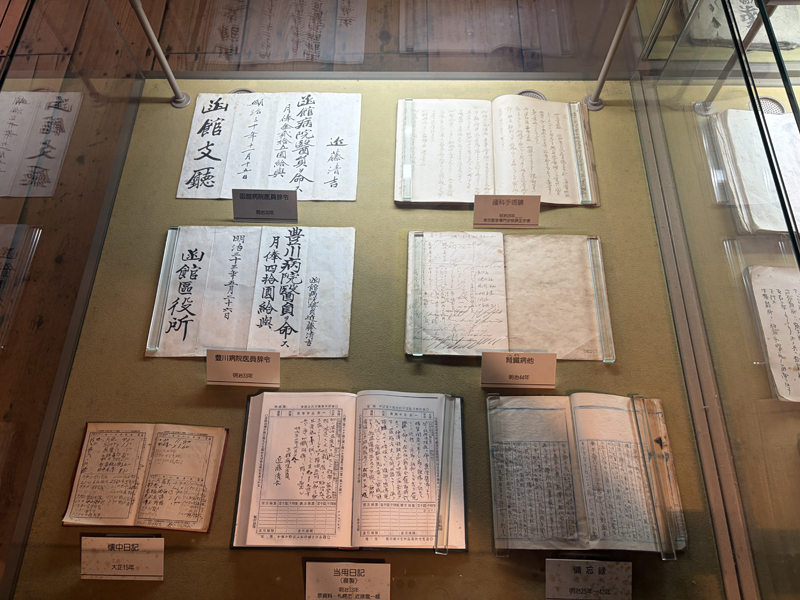 手書きの診療録（カルテ）。ドイツ語の専門用語や当時の独特の筆記体・崩し字で患者の症状や処置の記録が展示されている