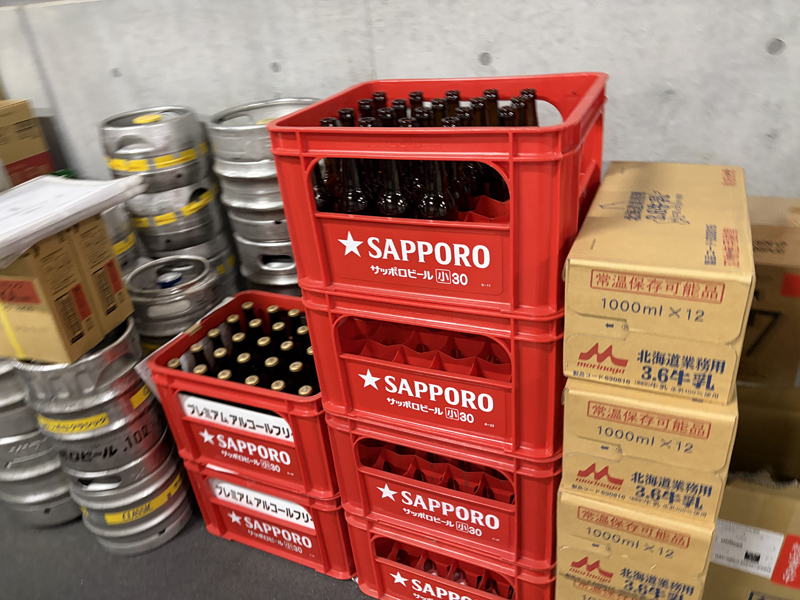 関係者以外立ち入り禁止のバックヤード通路にビールのケース、ビールの樽、箱に入った牛乳など積まれている様子